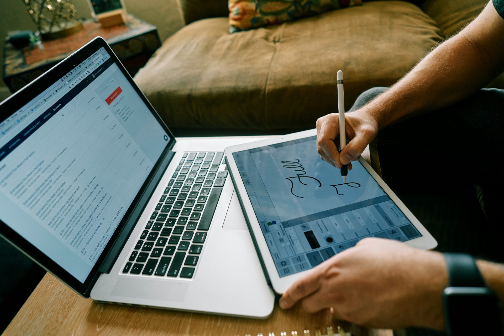 person using macbook pro on brown couch